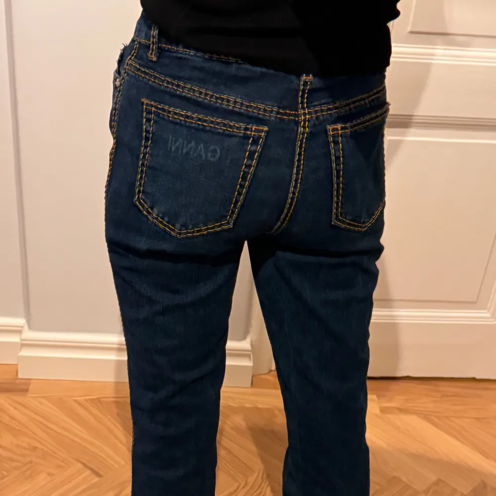 Mörkblåa Ganni jeans med gula sömmar! Jeansen är medelhöga i midjan och har en slits där fram nertill. De är i storlek 28 och fint skick!🫶. Jeans & Byxor.