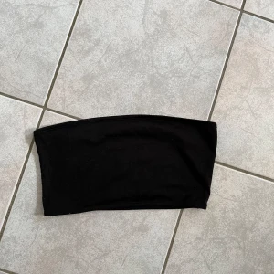 Svart tubtopp - Säljer en enkel och stilren svart tubtopp. Perfekt för sommardagar eller att ha under en kavaj för en festlig look. Toppen är i ett mjukt och stretchigt material som sitter bekvämt på kroppen. skriv vid frågor💗