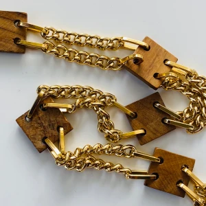 Guldfärgat kedjebälte med trädetaljer - Säljer ett unikt skärp med tjocka guldkedjor och fyrkantiga trädetaljer. Skärpet har en cool och modern design som verkligen sticker ut. Perfekt för att ge en extra touch till din outfit!