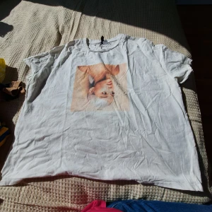 Vit t-shirt med tryck - Säljer en vit t-shirt med ett tryck av ett ansikte på framsidan och texten 'Sweetener' på baksidan. T-shirten är i en loose passform och perfekt för en avslappnad stil. Den är i bra skick och redo för en ny ägare!