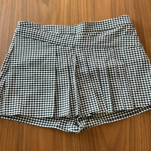 Svartvitrutiga shorts från Zara - Säljer ett par snygga svartvitrutiga shorts från Zara. De är högmidjade och har en klassisk rutigt mönster som ger en stilren look. Perfekta för både vardag och fest! 🖤