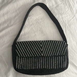 Axelremsväska  - Liten axelremsväska med svarta och silvriga pärlor Ny skick Knapp öppning  