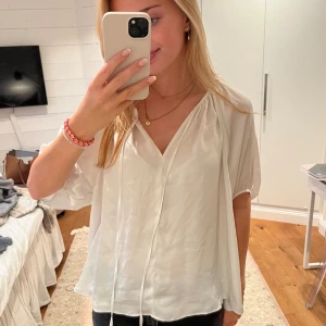 Vit blus med v-ringning - Säljer en superfin vit blus med v-ringning. Den har mellan långa armar. Materialet är lätt och luftigt! från hm 