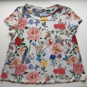 Blommig tshirt - Blommig tshirt, är märkt som storlek 158/164 men passar som storlek XS. Är knappt använd och därför mycket gott skick. Skriv vid frågor!