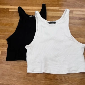 Svart och vit ribbad linnetopp från Zara - Två snygga ribbade linnetoppar från Zara i svart och vit. Perfekta för sommaren med en croppad passform som ger en trendig look. De är ärmlösa och gjorda i ett mjukt material som känns skönt mot huden.