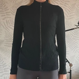 Svart ribbad tröja från Sweet Delicate - Säljer en svart ribbad tröja från Sweet Delicate i storlek XL. Den är liten i storleken och sitter som en S/M. Tröjan har en dragkedja framtill och är tillverkad av 65% bomull och 35% polyester. Perfekt för både höst och vinter med sin långärmade design. Superbekväm och stilren!