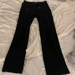 Svarta mjukisbyxor från Juicy Couture - Säljer ett par mjukisbyxor från Juicy Couture. Byxorna har fickor både fram och bak med knappar på bakfickorna. 