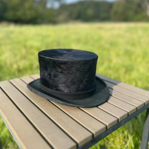 Svart hög hatt - Vintage italiensk handgjord hatt från Parma. Bra för formella tillfällen eller som en unik accessoar. Hatten har en slät yta och en fin inre detalj med ett emblem. Passar bra för både höst och vår.
