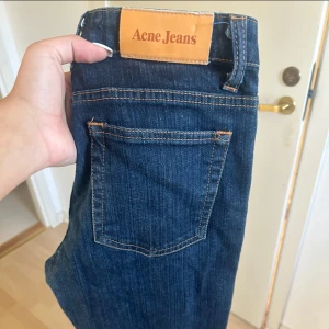 Mörkblå jeans från Acne - Säljer ett par klassiska lågmidjade raka mörkblå jeans från Acne. De har en snygg straight passform och är perfekta för vardagsbruk. Jeansen har de typiska fem fickorna och en knappgylf. Perfekta för både höst och vår!