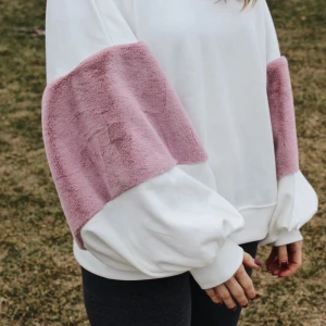 Vit tröja med rosa plyschdetaljer - Superfin vit tröja med fluffiga rosa plyschdetaljer på ärmarna. Den har en avslappnad passform och är perfekt för mysiga dagar. Tröjan är långärmad och har en rund halsringning. Perfekt för att hålla sig varm och stilren! Köpt från Zara för 399kr