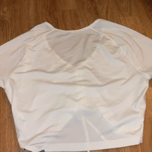 Vit scrunch t-shirt från ICANIWILL - Säljer en vit scrunch t-shirt från ICANIWILL i storlek S. Den är tillverkad av 87% polyamid och 13% elastan, vilket gör den superstretchig och bekväm. T-shirten har en snygg scrunch-detalj framtill och är croppad, perfekt för träning eller en avslappnad look. Den har korta ärmar och en justerbar passform tack vare snörningen.