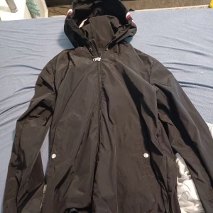 Svart vindjacka med huva - Säljer en snygg svart vindjacka från Moncler. Den är storlek L men passar även M hör va är om ni har frågor