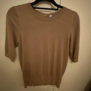 Beige tröja från Pulz - Säljer en stilren beige tröja från Pulz med trekvartsärm och knappar i nacken. Perfekt för en avslappnad look. Tröjan har en rund halsringning och är tillverkad i ett mjukt material knappt andvänd