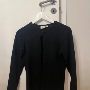 Svart kofta från Saint - Säljer en stilren svart kofta från Saint i storlek xs. Koftan har långa ärmar och knappar framtill. Perfekt för lager-på-lager-stil eller som ett enkelt basplagg i garderoben.
