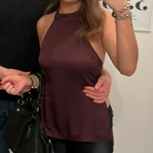 Vinröd halterneck topp - Superfin halterneck topp som knyts med rosett i ryggen. Liten slitning men ingnet som syns på håll, använd en gång. Köpt för 499kr