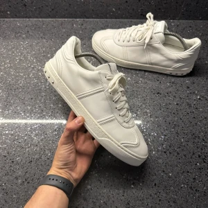 Valentino Flycrew - Stilrena och lyxiga Valentino Flycrew sneakers i vitt! En perfekt kombination av komfort och exklusiv design. Notera att en nit saknas, men skorna behåller ändå sin eleganta look.  | Färg: Vit ⚪✨ | Skick: Bra skick, men en nit saknas ⚠️ | Modell: Flycrew 🏆 | Storlek: 40 👌 | Tillbehör: Endast skorna ingår 👟  🚚 |Leverans: Skickas snabbt via PostNord eller Instabox 📬📦 | 💬 Skicka ett meddelande vid frågor!