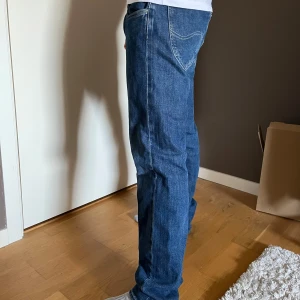 Blå jeans från Lee - Säljer ett par klassiska blå jeans från Lee. De har en straight passform med normal midja och snygga sömmar. Perfekta för en avslappnad stil. Bara använda ett fåtal gånger. Säljer pga att de är lite stora för mig.