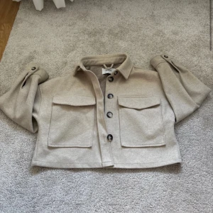 Beige overshirt från Stradivarius - Säljer en snygg beige overshirt från Stradivarius. Den har stora knappar och två framfickor. Perfekt för lager-på-lager-stil. Passar bra till både jeans och kjol. 🧥finns en liten liten fläck som man knappt ser.