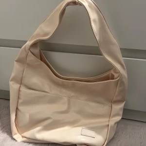Beige axelväska - Snygg beige clutch axelväska i syntetmaterial. Perfekt för att bära med sig det nödvändigaste. Stort fack och två små. Vet inte vart den är ifrån då jag köpte den på en TikTok reklam! Använd 1 gång! 