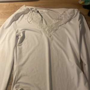 Vit långärmad topp med spetsdetaljer - Jag säljer denna fina bodyn! Den är i storlek S! Perfekt till alla årstider, helt i ny-kvalité!🩷Köpt i Spanien på shoppingcenter🤩🙏🏼