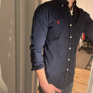 Ralph Lauren Skjorta - Tja säljer en Ralph lauren skjorta i färgen marinblå och i storlek S passar 170-180 cm ungefär. Nypris 1595 KR mitt pris 299 KR. Inga defekter som hål eller fläckar. Skriv vid frågor eller funderingar.