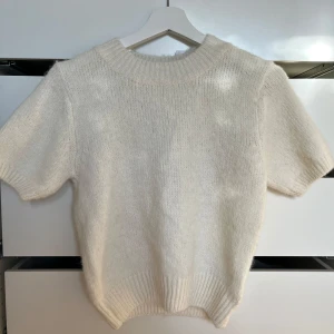 Vit stickad tröja - Mysig vit stickad tröja med korta ärmar och ribbad kant vid hals och nederdel. Perfekt för kyliga dagar och ger en stilren look. Helt ny med lapparna kvar! Skriv om ni har några frågor! 💞