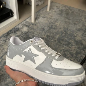 Grå och vita sneakers från Bape - Snygga sneakers från Bape. Skorna är lite glänsiga som man ser. Dom är ej använda så helt nya.