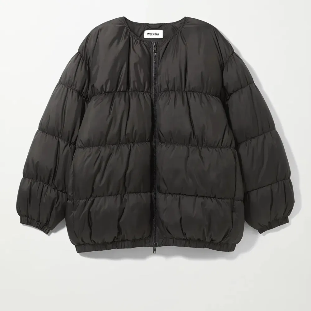 Snygg svart pufferjacka model Kai från Weekday. Jackan har en oversized passform och långa ärmar, perfekt för kyliga dagar. Den quiltade designen ger en modern look. . Takit.