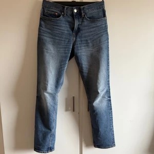 Blå slim jeans från H&M - Snygga blå slim jeans från H&M med klassisk femficksdesign och knappgylf. Perfekta för en stilren look. Tillverkade i ett bekvämt denimtyg som ger en skön passform.