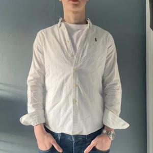 Ralph Lauren skjorta - Säljer en stilren vit skjorta från Ralph Lauren i storlek XS slimfit. Säljer pga att den är för liten. Passar dig som är ca 150-170cm. Hör av dig vid frågor och funderingar!