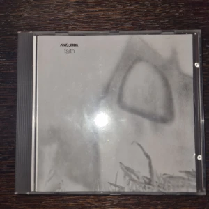 Faith - The cure cd - CD-albumet 'Faith' av The Cure, utgivet av Fiction Records. Innehåller låtar som 'The Holy Hour', 'Primary' och 'Faith'. CD:n har en klassisk design med tydlig låtlista på baksidan. Repig utvändigt.