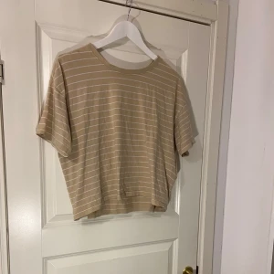 Beige och vit randig t-shirt - Säljer en beige och vit randig t-shirt från Etirel.