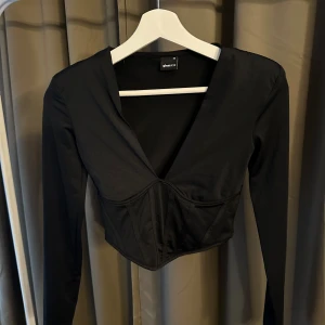 Svart långärmad topp från Gina Tricot - Snygg svart fest topp från Gina Tricot. Korsett detalj, superskönt material 