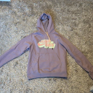 Lila hoodie från Jordan - Säljer en snygg lila hoodie från Jordan med texten 'Jumpman' i färgglada bokstäver på bröstet. Hoodien har en justerbar huva med mönstrat foder och en praktisk magficka. Perfekt för en avslappnad stil!