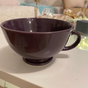 Kopp stor  - Säljer en stor och rymlig kopp i en djup lila färg. Perfekt för te eller kaffe, med ett bekvämt handtag för enkel användning. Koppens stilrena design gör den till ett snyggt tillskott i köket.16dia
