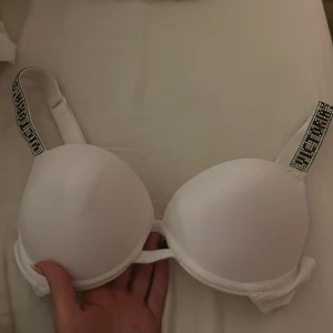 Vit bh med dekorerade axelband - Snygg vit bh med vadderade kupor och dekorativa axelband med pärlor. Perfekt för att ge en extra touch till din outfit. Justerbara band för bästa passform.