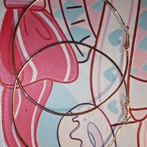 Guldfärgade stora hoop-örhängen - Säljer ett par stora guldfärgade hoop-örhängen. De är tunna och eleganta, perfekta för att ge en stilren touch till din outfit. Lätta att bära och passar till många olika stilar.