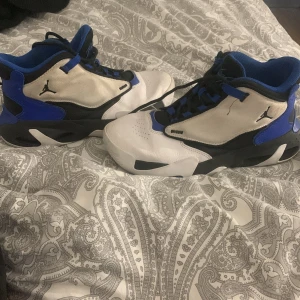 Nike Air Jordans i blått och vitt - Snygga Nike Air Jordans i blått, vitt och svart. Skorna har en klassisk design med snörning och den ikoniska Jumpman-loggan på sidan. Perfekta för dig som vill ha en stilren och sportig look. 