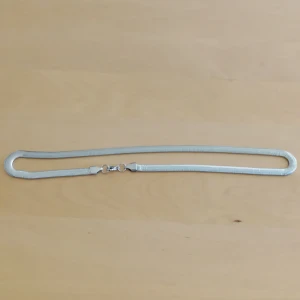 Silverfärgat halsband - Elegant silverfärgat halsband med en ormliknande kedja. Perfekt för att ge en stilren touch till din outfit. Kedjan är smidig och har en enkel låsning.