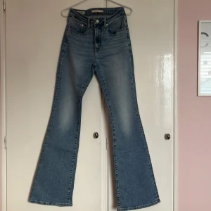 Blå bootcut jeans från Levi's - Snygga blå bootcut jeans från Levi's med klassisk femficksdesign och hög midja. Perfekta för en avslappnad stil med en touch av retro. Levi's logotyp på baksidan ger en autentisk känsla. Dem är i storlek 27x34 (midja 27cm och längd 34cm). Dem är i bra skick och säljes pga de inte kommer till användning längre. Priset kan förhandlas. Nypris 1299kr. 