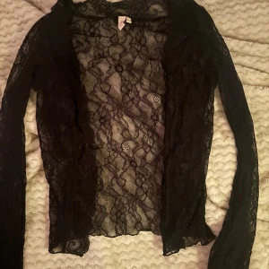  spetsblus från nelly med knappar - Säljer en svart spetsblus med långärmad design. Perfekt för att lägga till en touch av stil till din outfit. Blusen är genomskinlig och har ett vackert mönster i spetsen. I storlex xxs och från nelly! Ändast använd 2 gång.