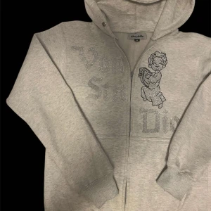 Grå hoodie med strassdetaljer från Vondutch - Snygg grå hoodie från Von studio med strassdetaljer och ett tryck av en ängel på framsidan. För 300 kr 