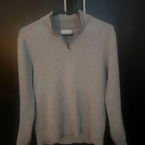 Grå stickad tröja från These Glory Days(brothers) - Säljer en stilren grå stickad tröja från These Glory Days. Tröjan har en dragkedja vid halsen och långa ärmar.  Skick 10/10. Väldigt fräsch zip till våren. Diskutera pris i dm.