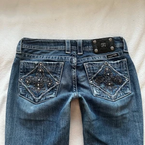 Lågmidjade bootcut miss me jeans  - As coola miss me jeans med slitningar i storlek 28. Tvärs över midjan är de 39cm och innerbensländen är 86cm