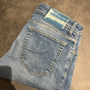 Jacob Cohen jeans  - Snygga ljusblå jeans från Jacob Cohen med knappgylf och klassisk femficksdesign. Jeansen har en stilren look med subtila slitningar och kontrastsömmar. Perfekta för en avslappnad stil.