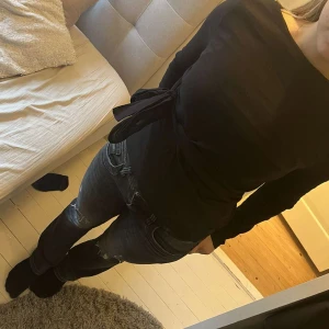 Svart långärmad topp från Zara - Säljer en stilren svart långärmad topp från Zara. Toppen har en elegant knytning i midjan som ger en fin siluett. Perfekt för att skapa en chic look. 🖤