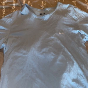 Ljusblå t-shirt från Boss - Snygg ljusblå t-shirt från Boss med diskret broderad logga på bröstet. I storlek XL, väljer ni att köpa både den vita och denna tillsammans blir det 200kr