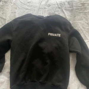Svart sweatshirt med texten 'PRIVATE' - Säljer en svart sweatshirt med texten 'PRIVATE' tryckt på bröstet. Tröjan har en klassisk design med rund hals och långa ärmar. Perfekt för en avslappnad stil.