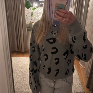 Grå leopardmönstrad tröja - Säljer en snygg grå tröja med leopardmönster. Tröjan har långa ärmar och den är jätte mjuk . Säljer den för att den inte kommer till användning och det är inga defekter på tröjan❤️den är i M men den sitter som en S