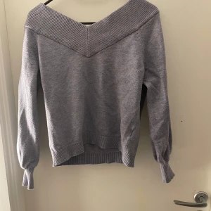 Grå tröja från Jacqueline de Yong - Säljer en stilren grå tröja från Jacqueline de Yong. Tröjan har en v-ringad design med ribbade detaljer vid halsen och ärmsluten. Perfekt för en avslappnad och trendig look.